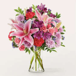 Pink lilies and mixed flowers in a clear glass vase