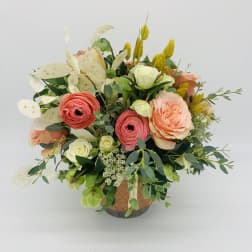 Peach and coral roses with white blooms arranged in a decorative ceramic pot.