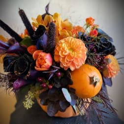 Orange and black floral arrangement with pumpkins and autumn blooms