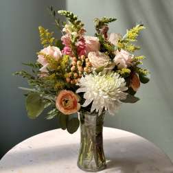 Mixed bouquet of pale pink and white flowers in a clear glass vase