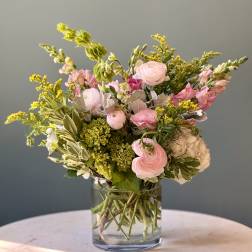 Pink and white flowers arranged in a clear glass vase