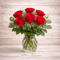 Red roses arranged in a clear glass vase with baby's breath