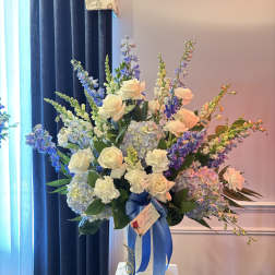 Large bouquet of white roses, blue flowers, and hydrangeas in a white vase