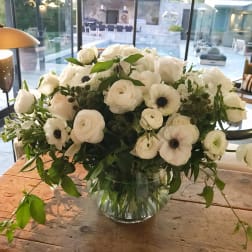 White floral arrangement in a clear glass vase on a wooden table