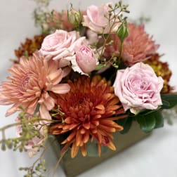 Pink roses and orange chrysanthemums arranged in a low box