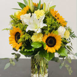 Bouquet of sunflowers, white lilies, and yellow carnations in a glass vase