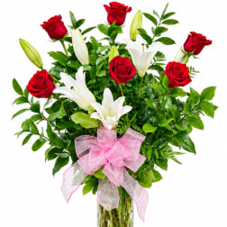 Bouquet of red roses and white lilies in a glass vase with a pink bow