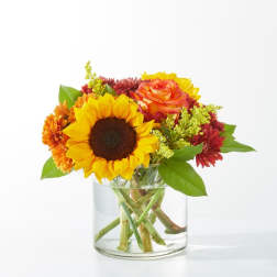 Sunflower and mixed autumn flowers in a clear glass vase