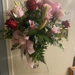 Bouquet of pink and red roses with lilies in a glass vase