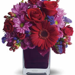 Red and purple mixed bouquet in a clear square vase