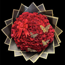 Round bouquet of red roses with red bow and gold butterfly accents in black and gold wrap