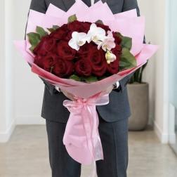 Man holding a bouquet of red roses wrapped in pink paper
