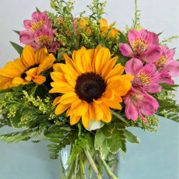 Bouquet of yellow sunflowers and pink alstroemeria in a glass vase