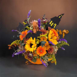 Halloween floral arrangement in an orange container with black house cutouts