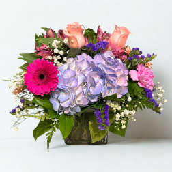 Mixed bouquet with hydrangea, roses, and gerbera daisies in a glass vase