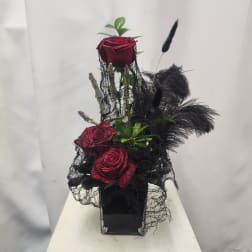 Red roses in a black vase with black feathers and netting