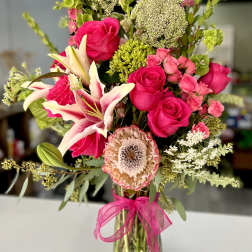 Pink roses and lilies in a glass vase with a pink ribbon