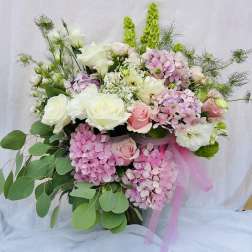 Bouquet of pink and white roses with hydrangeas and greenery, tied with pink ribbon