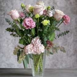 Pink roses and carnations in a clear glass vase