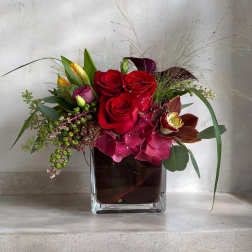Red roses and pink orchids in a square glass vase