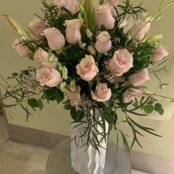 Pink roses arranged in a white vase with greenery