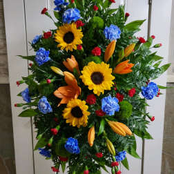 Standing floral spray with sunflowers, lilies, and carnations in bright colors