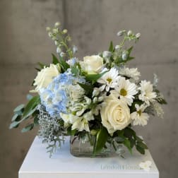 White and blue floral arrangement in a clear glass vase