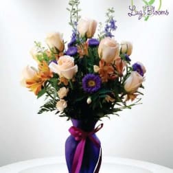 Bouquet of pale roses and purple flowers in a purple vase with ribbon