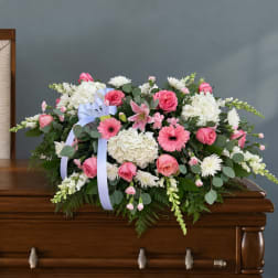 Pink and white floral casket spray with a lavender ribbon