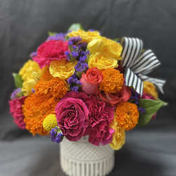 Bright mixed bouquet in a white vase with a striped ribbon