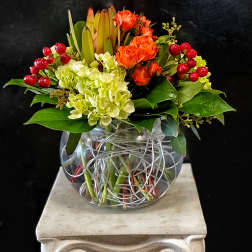 Orange roses and pale hydrangeas in a clear glass vase