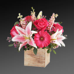 Pink roses and lilies arranged in a wooden box