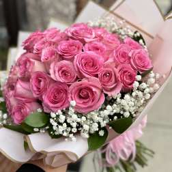 Bouquet of pink roses with white baby's breath in pale pink wrap