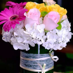 Mixed bouquet in a green vase with pink, yellow, and white flowers