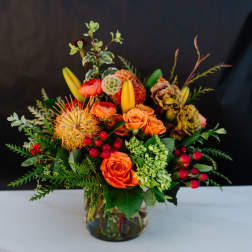 Orange roses and mixed blooms arranged in a glass vase