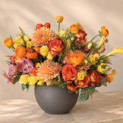 Mixed orange, yellow, and red flowers arranged in a dark vase