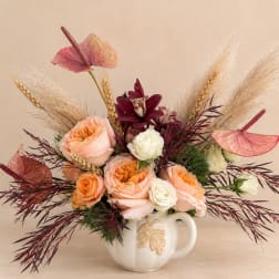 Peach and white roses in a white ceramic mug with dried grasses