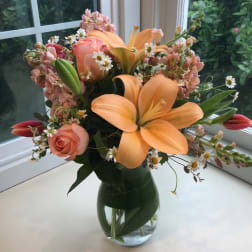 Peach lilies and roses in a glass vase