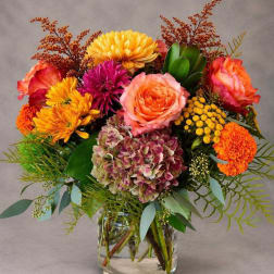 Colorful bouquet of roses, chrysanthemums, and hydrangea in a clear glass vase