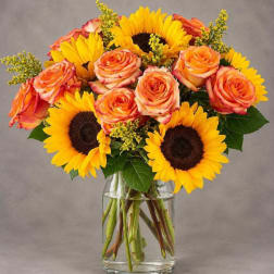 Bouquet of orange roses and sunflowers in a clear glass vase