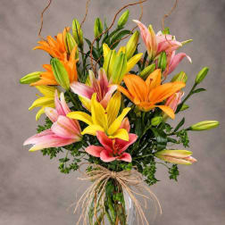 Bouquet of pink, yellow, and orange lilies in a clear vase