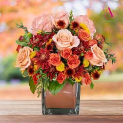 Peach and coral roses with pink hydrangeas in a square glass vase