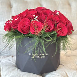 Red roses arranged in a black box with greenery