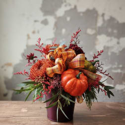 Fall arrangement with orange flowers, pumpkins, and plaid ribbon in a burgundy pot