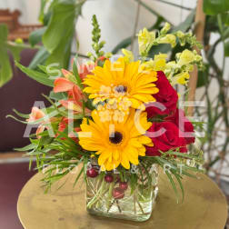 Yellow gerberas and red roses in a square glass vase
