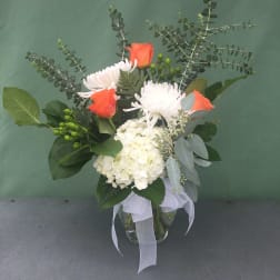 Bouquet of orange roses, white chrysanthemums, and white hydrangea in a glass vase