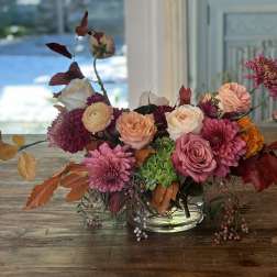 Mixed pink and peach flower arrangement in a clear glass bowl