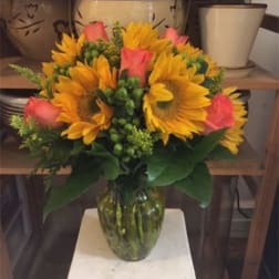 Bouquet of sunflowers and pink roses in a glass vase