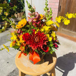 Bright mixed bouquet in a glass vase with red, yellow, and orange flowers