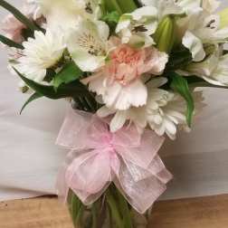 White and pale pink bouquet in a glass vase with a pink ribbon